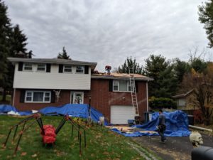 The roof of the house partially open because the workers are replacing plywood before they put the shingles on. Also, our giant red spider for Halloween is in the foreground.