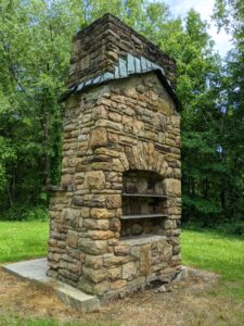 A fireplace that used to be inside of a cabin. It is about 20 feet tall and made of stone.