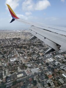 Looking out the airplane window. Part of the wing is visible.  San Diego is sprawled out below us, the Pacific Ocean in the distance.