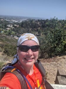 A selfie of me on top of Mt. Soledad. San Diego is in the background. I'm smiling.