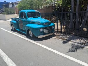 A blue older truck parked on a road. It's a Tequila truck and it's lowered and totally impractical.