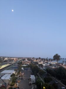 Looking off of the roof of the hotel where the pool is. It's getting to be night, the moon is up and almost full. The sky is clear. Overlooking Oceanside.