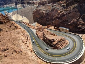 Hoover Dam. This is the road leading to it. It's a switchback, seen from above. There are red rocks everywhere and the dam is in the background.