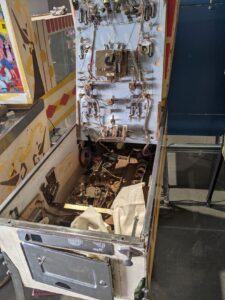 A pinball machine that's opened up so you can see the inside mechanical stuff.