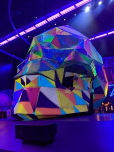 A giant skull with color blocks all over it and lit by blacklight.