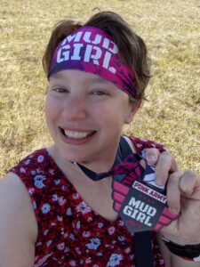 Selife with my Mud Girl medal and headband on. I'm not very muddy and wearing a red flowered dress and a big smile! My hair is short and looks fab.