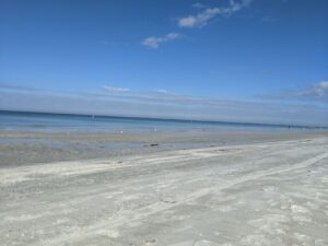 Indian Rocks Beach, Tampa, Florida. It's a blue sky with a few clouds and the water is calm. The beach is white sand, soft.