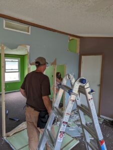 My sister's house, the middle wall that we took down (not load bearing!) - my niece is working on removing it while Gabe stands by a ladder in the foreground supervising.