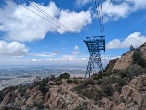 Sandia Tramway - a view out the western-facing window of a ridge with one of the support structures on it. Albuquerque is in the background. Blue sky, a few clouds, gorgeous day.