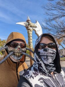 Gabe and I dressed up. He's wearing a mask that's like a skull with pipes coming out of it - he calls it his Mad Max mask. I'm wearing a hooded shirt with white tree-like patterns and a face covering that's the bottom half of a skull.