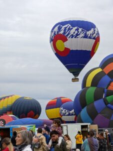 The Albuquerque Balloon Fiesta, 50th Anniversary, balloons inflating on the field with a Colorado balloon going up in the air. 