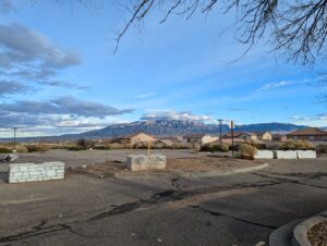 A view of the Sandia Mountains from the old country club parking lot. There is snow on the highest peaks and the sky is blue with some clouds moving in.