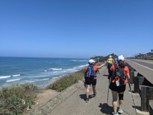 Project Athena San Diego, women walking along a path by the Pacific Ocean. Blue sky, perfect day.